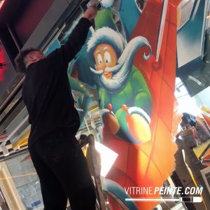 Peinture sur vitrine de Noël représentant un Père Noël géant voyageant dans l'espace