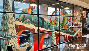 Décoration tendance 2026 : peinture de Noël réalisée à la main sur une vitrine de magasin.