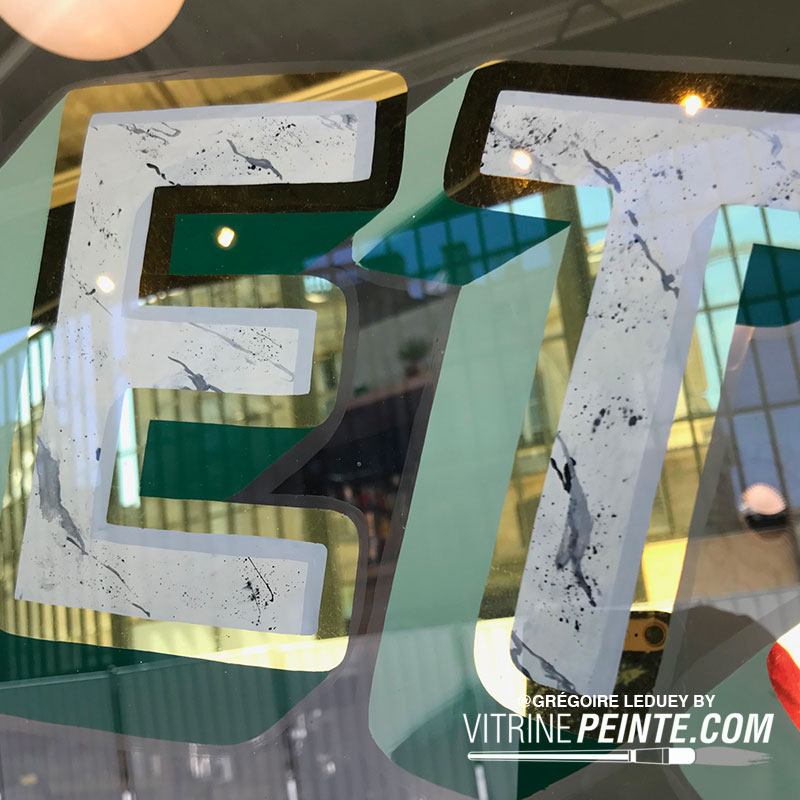 Vitrine de magasin décorée avec lettrage à la feuille d’or, finition luxueuse et raffinée pour une visibilité élégante