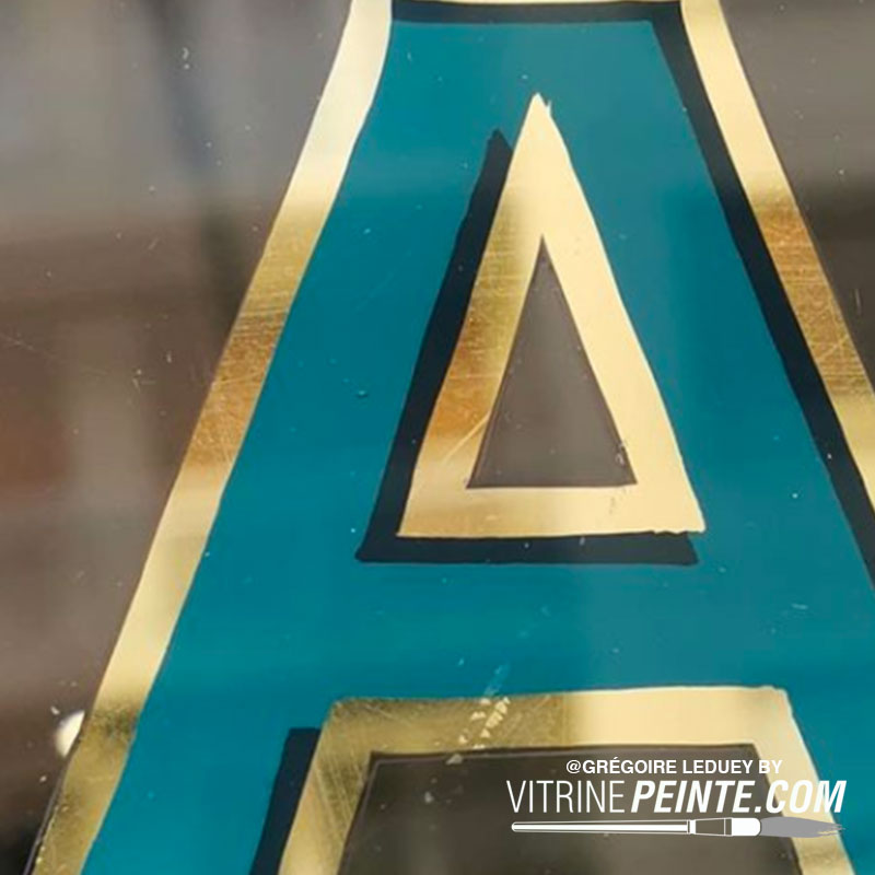 Lettrage à la feuille d’or sur vitrine de magasin, décor élégant et luxueux pour attirer l’œil et sublimer votre commerce.
