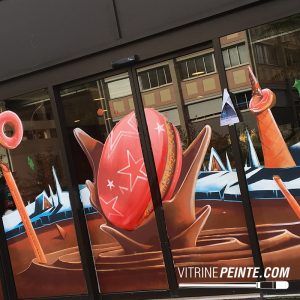 Macaron rose géant et rivière de chocolat sur une vitrine de magasin, idée de décoration gourmande, créative et spectaculaire.