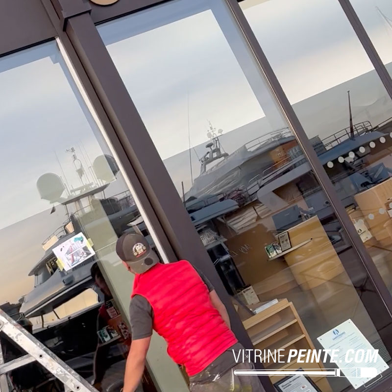 Personne devant une vitrine vide hésitant entre peinture sur vitre et sticker