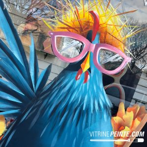 Décoration de vitrine opticien pour Pâques avec poule géante portant des lunettes, intégrée dans une opération de merchandising créatif pour attirer les clients.
