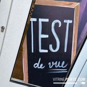 Merchandising de vitrine pour opticien avec test optique géant sur tableau noir XXL, une décoration originale qui capte le regard et dynamise le point de vente. Décoration et merchandising de vitrine d'opticien avec tableau noir format XXL et test de vue