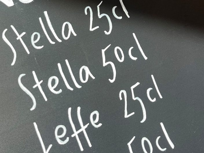 Lettrage artisanal sur tableau noir avec illustrations à la craie et décoration d'ardoise murale pour restaurant et bar