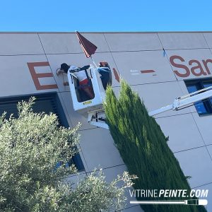 Création d’une enseigne peinte à la main format XXL sur bardage composite, avec lettrage peinture réalisé par un artisan signalétique.