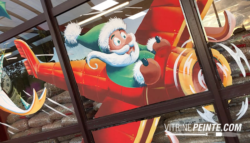 décoration peinture vitrine magasin Père Noël géant dans un avion – livraison express de cadeaux