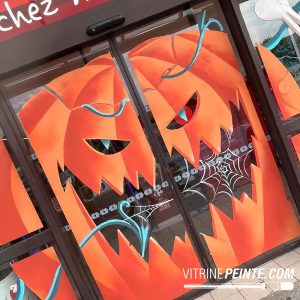 Décoration Halloween peinte à la main avec une tête de citrouille géante sur la porte automatique d'un magasin GSS