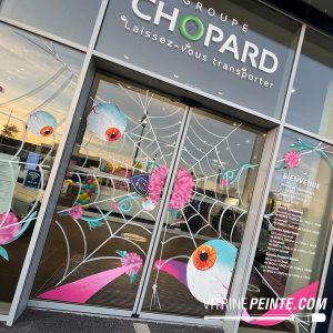 Décoration vitrine Halloween : une toile d'araignée géante en fils phosphorescents habille l'entrée d'un magasin