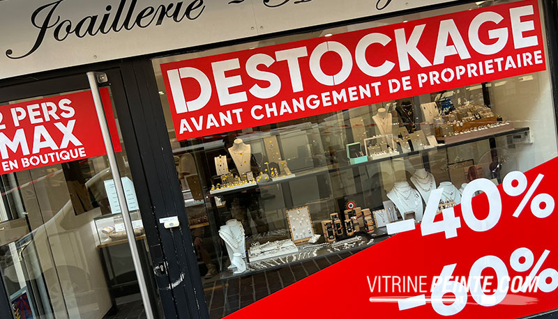 grand sticker déstockage peint sur vitrine de commerce