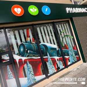 Peinture sur vitrine d’une pharmacie représentant unedécoration de Noël féerique pour une vitrine immersive et festive avec un trai format XXl