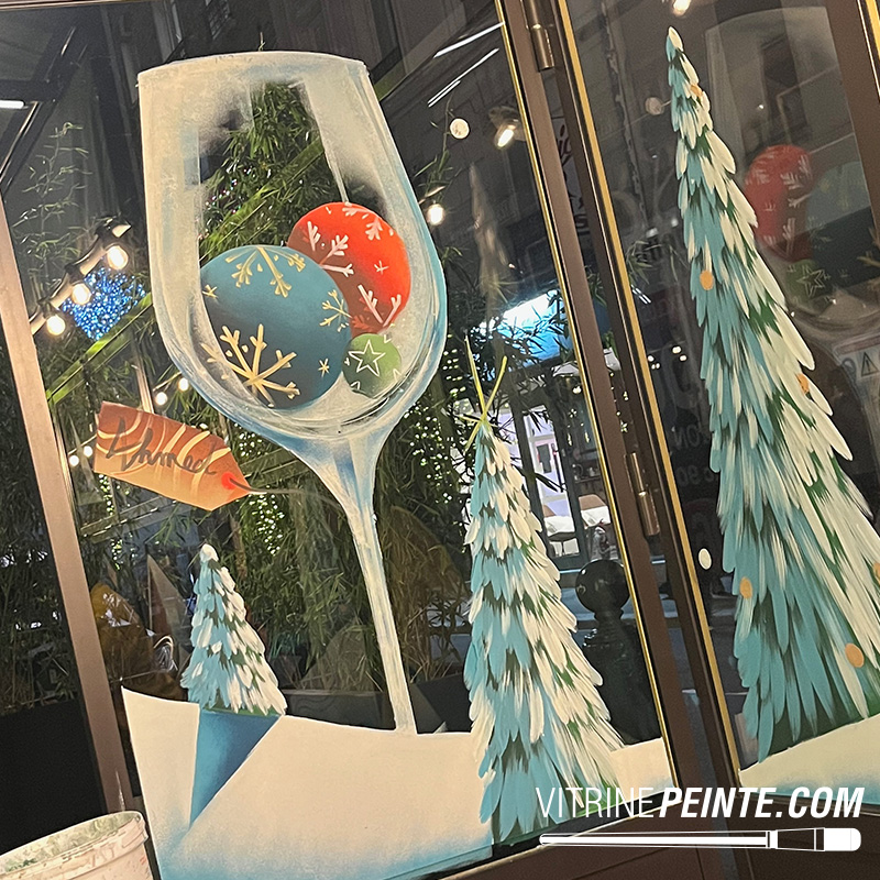 Verre à vin géant décoré pour Noël avec des boules de Noël à l’intérieur, idée de décoration peinture sur vitrine festive et originale.