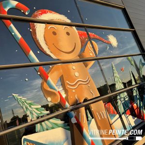 Peintres en vitrine réalisant une décoration de Noël pour un magasin