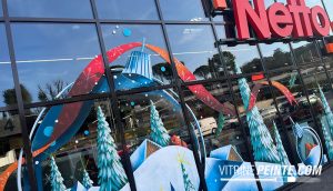 Décoration de vitrine de centre commercial pour Noël avec une boule à neige géante peinte sur vitrine, création festive et féerique.