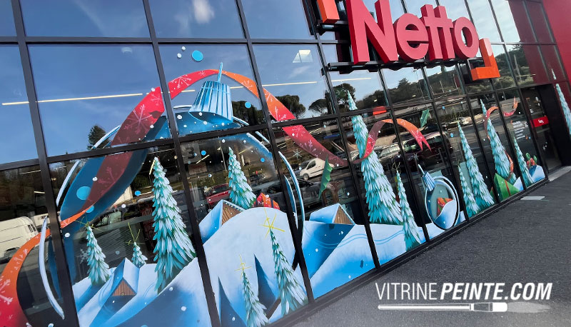 Décoration de vitrine de centre commercial pour Noël avec une boule à neige géante peinte sur vitrine, création festive et féerique.